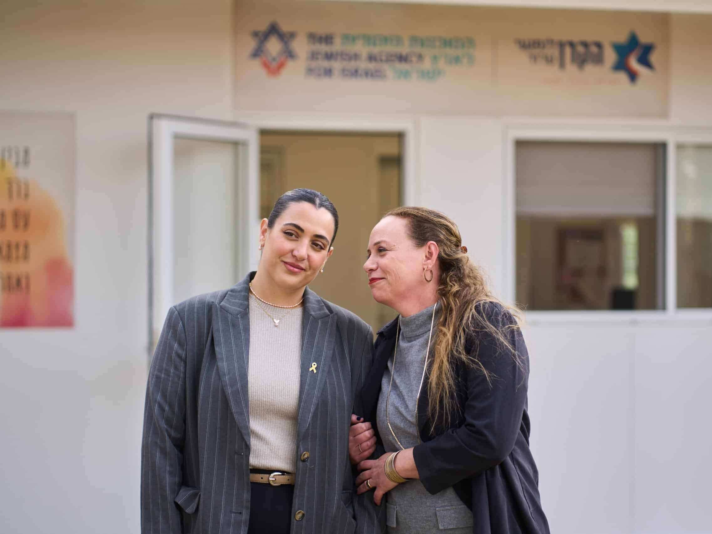 A female therapist smiles and holds the arm of a woman on a Kibbutz