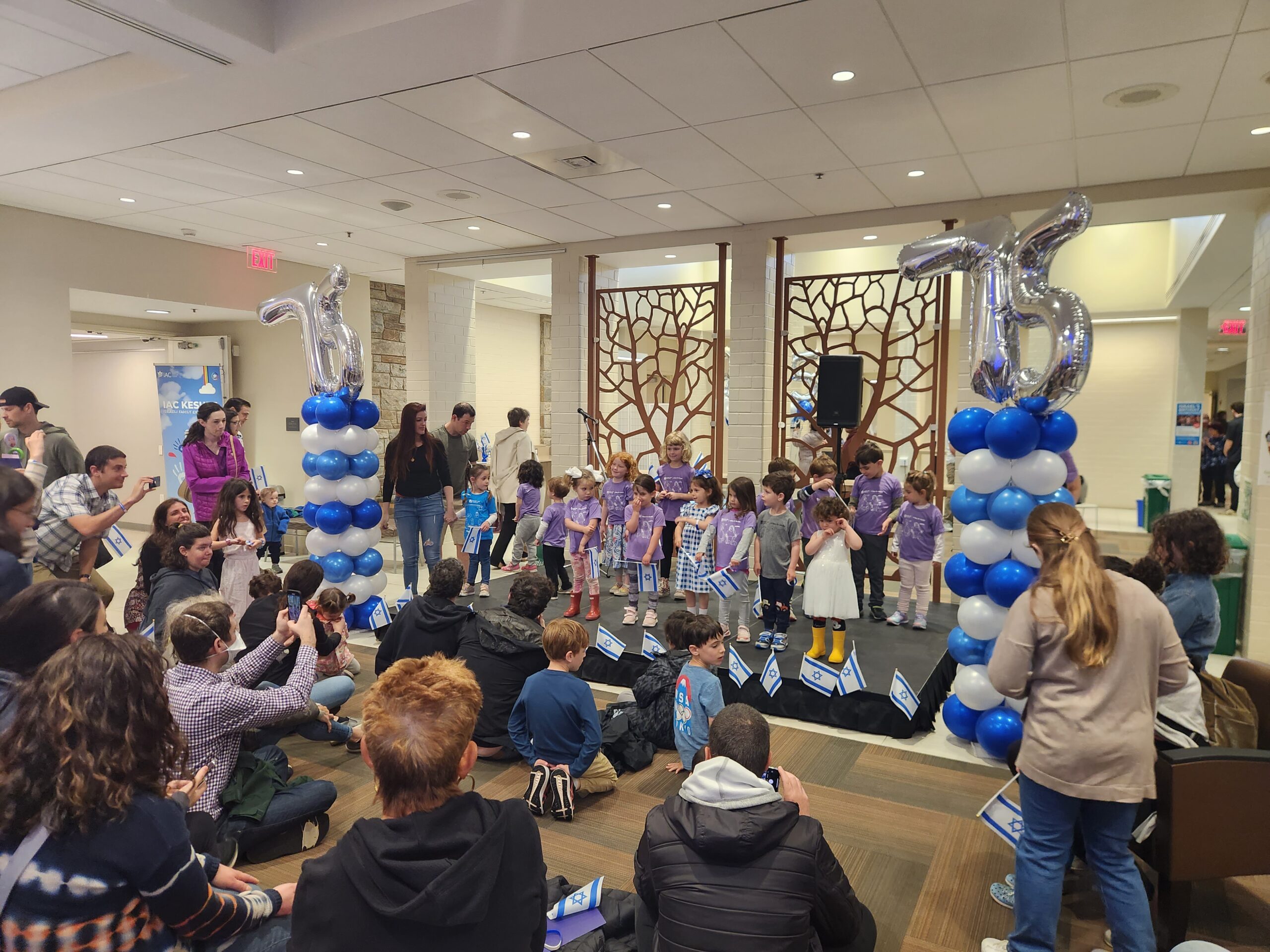 Children stand on the Bemah surrounded by balloons, celebrating Israel's birthday.