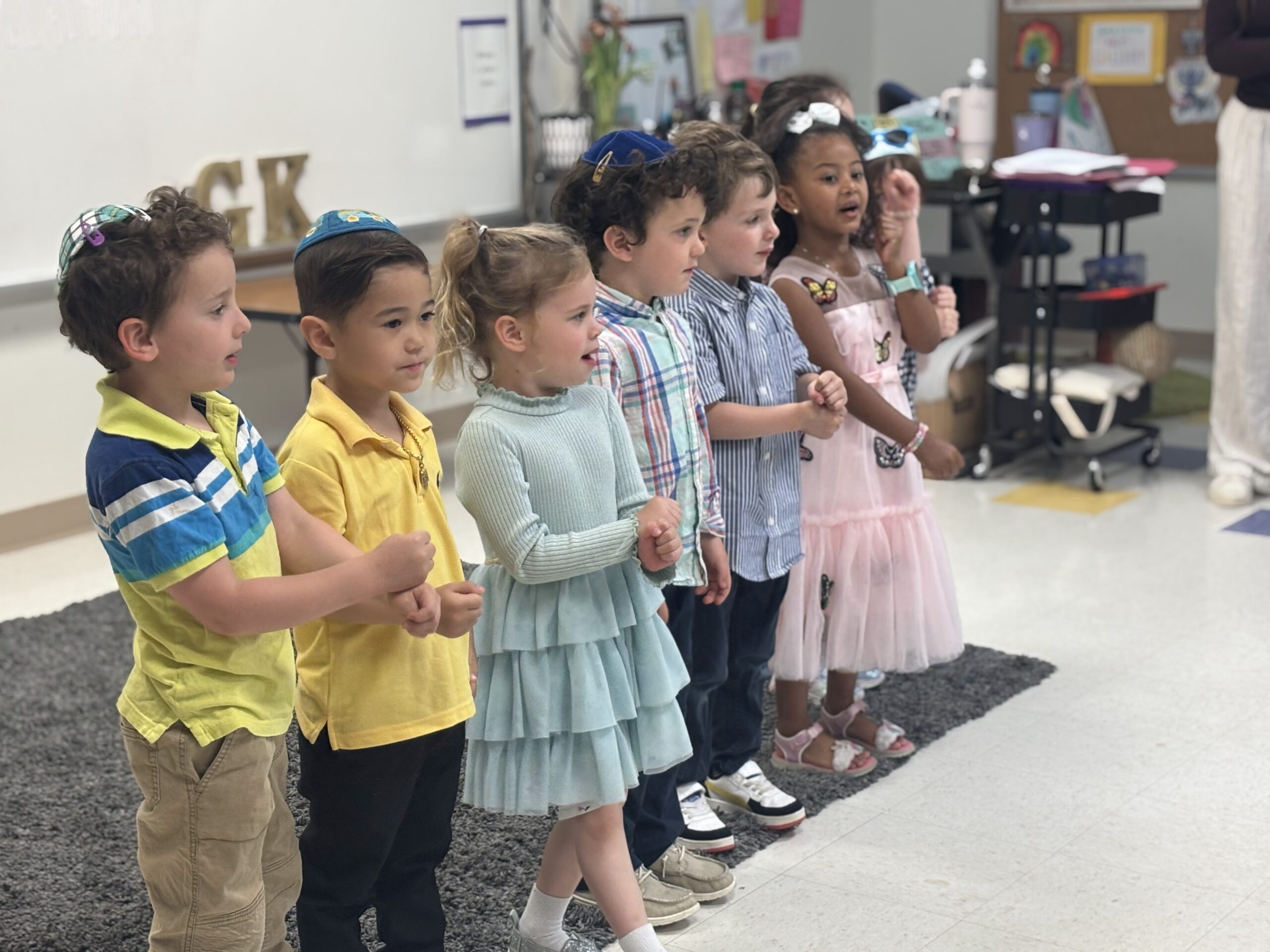 Preschool children standing in a line singing.