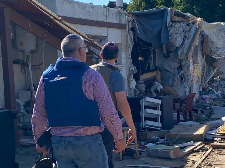 People wearing protective vests, walking through wreckage in Israel.