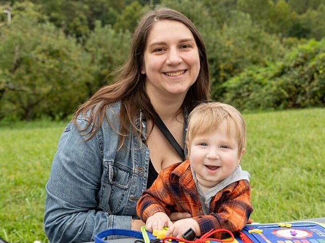 A mother and her toddler sit at a table outdoors