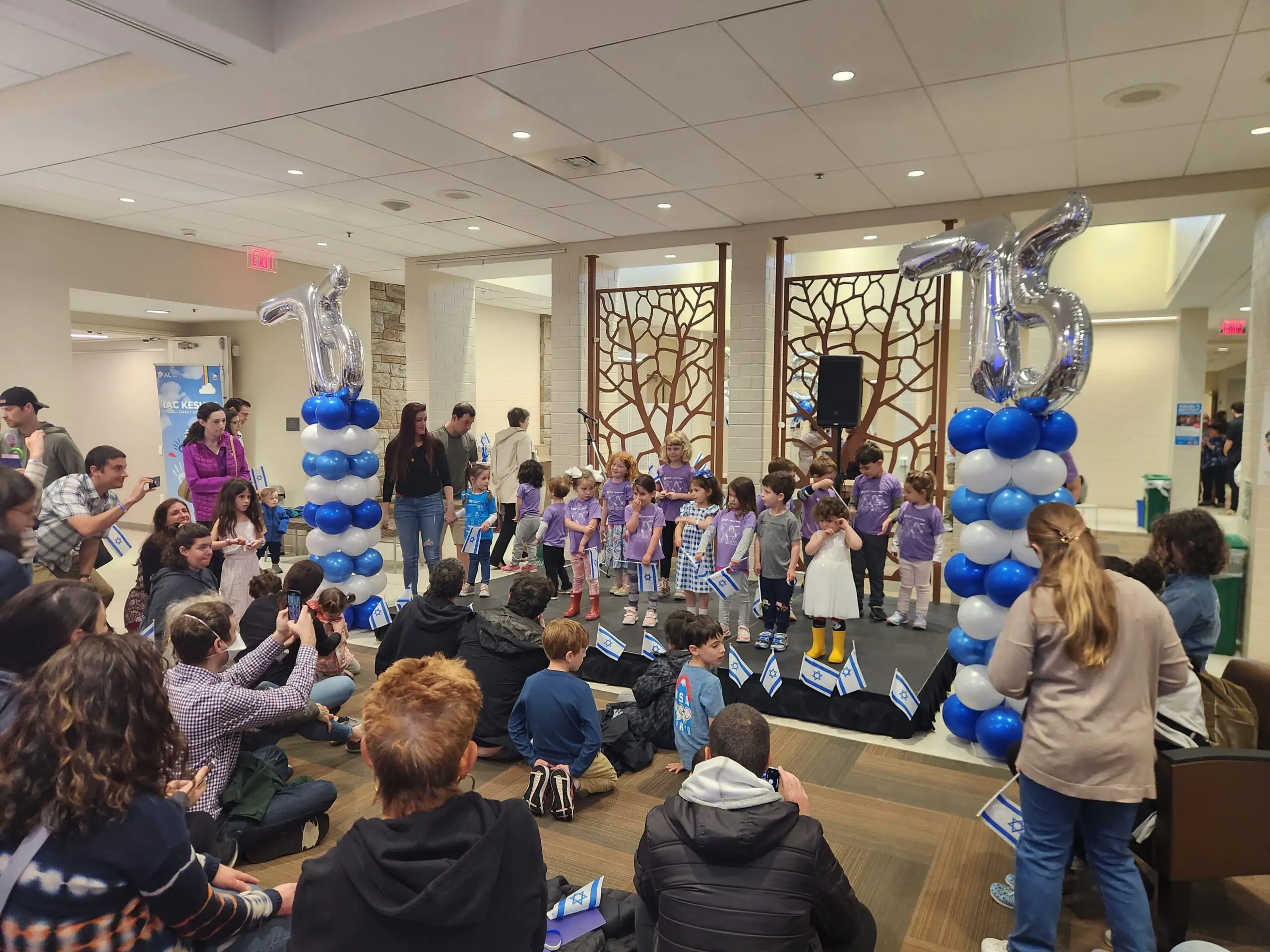 Children stand on the Bemah surrounded by balloons, celebrating Israel's birthday.