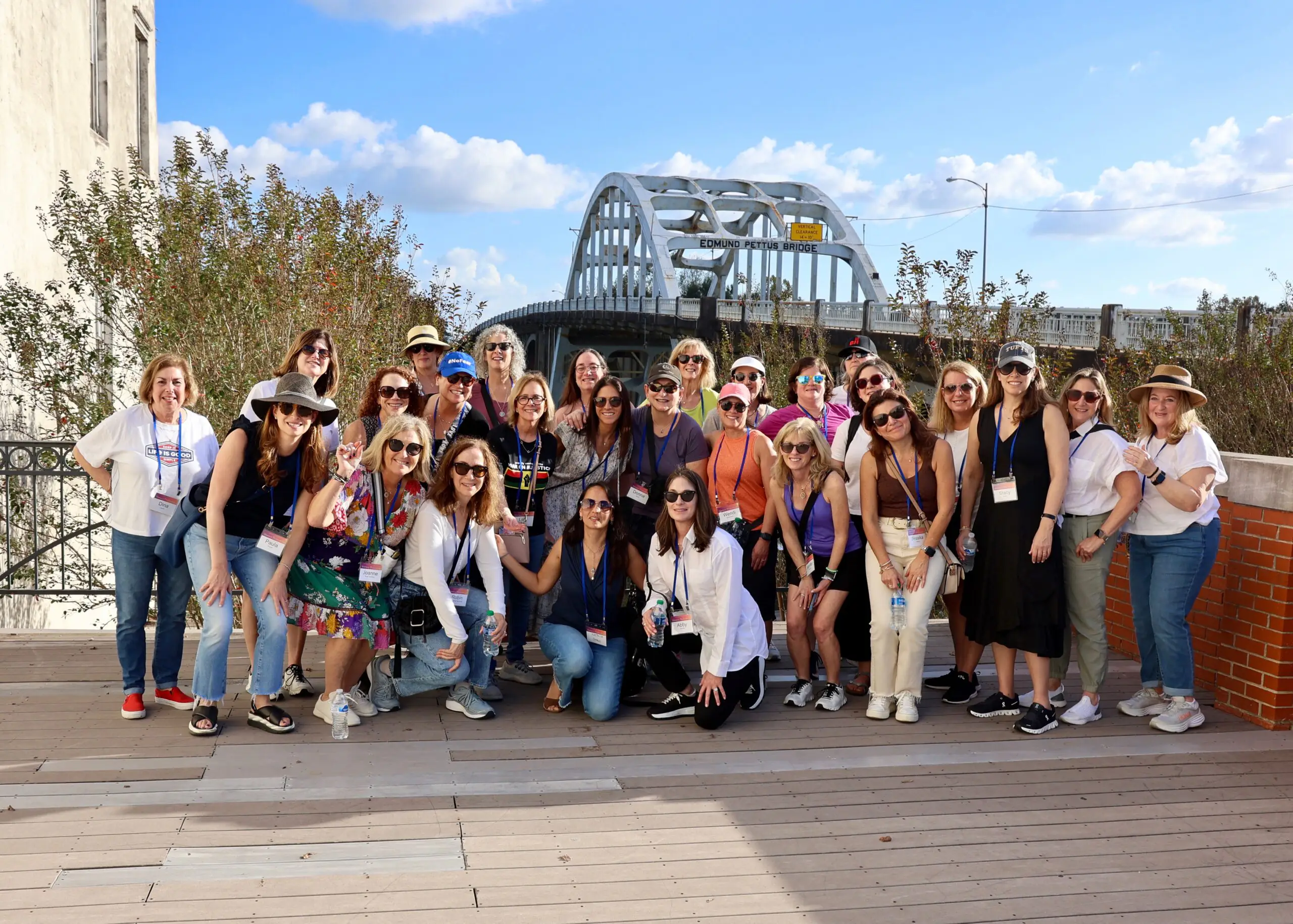 Large group of women pose on a bridge.