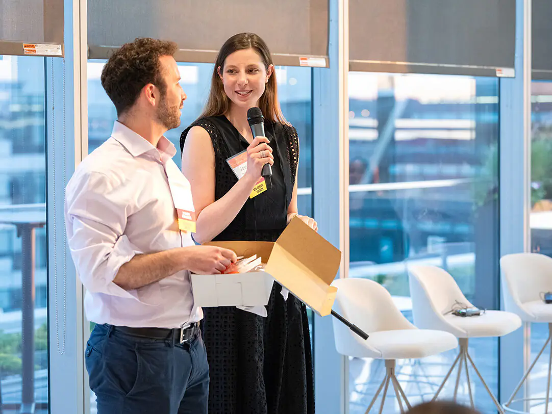 A woman holding a microphone, speaking to a man, leading a presentation during the Ben Gurion Society Spring event.